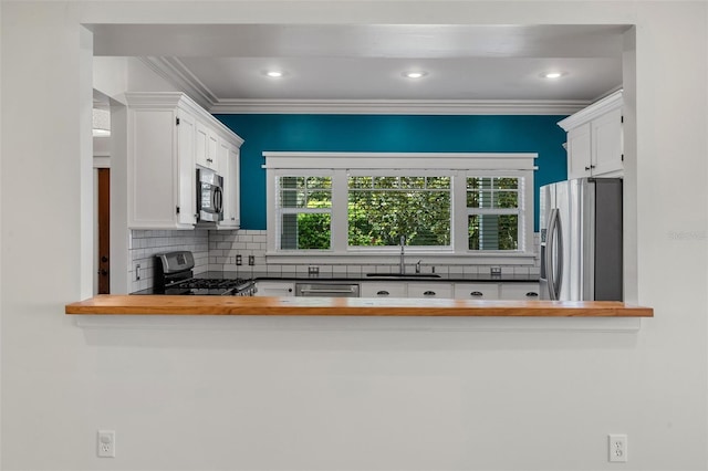 408 W Pearl St, Minneola, FL 34715 - kitchen featuring appliances with stainless steel finishes, tasteful backsplash, white cabinets, butcher block countertops, and crown molding