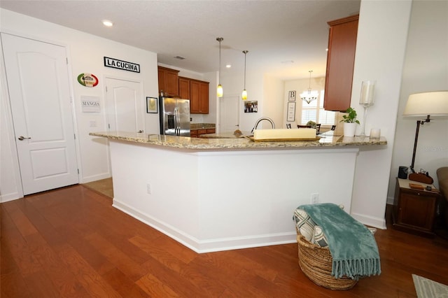 3574 La Jolla Dr, Clermont, FL 34711 - kitchen featuring stainless steel refrigerator with ice dispenser, brown cabinets, a peninsula, dark wood-type flooring, and light stone counters