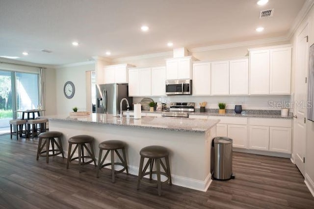 351 S Sunset Ave, Mascotte, FL 34753 - kitchen with stainless steel appliances, ornamental molding, a kitchen breakfast bar, a center island with sink, and white cabinets