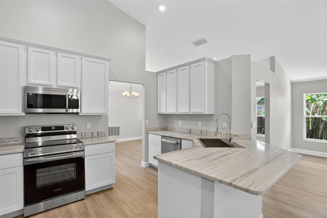 632 Bridge Creek Blvd, Ocoee, FL 34761 - kitchen with appliances with stainless steel finishes, a peninsula, high vaulted ceiling, a chandelier, and white cabinetry