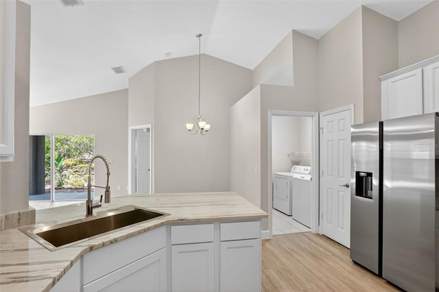632 Bridge Creek Blvd, Ocoee, FL 34761 - kitchen with stainless steel fridge, separate washer and dryer, high vaulted ceiling, a chandelier, and white cabinetry