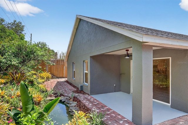 632 Bridge Creek Blvd, Ocoee, FL 34761 - view of home's exterior with a patio area, stucco siding, roof with shingles, a ceiling fan, and a small pond