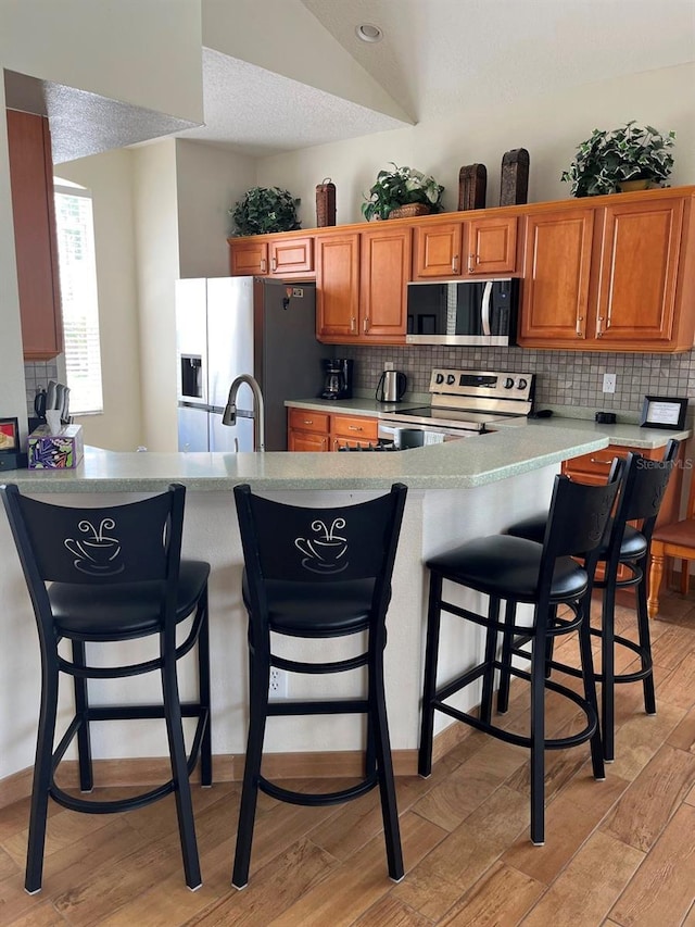 160 Calabay Parc Blvd, Davenport, FL 33897 - kitchen featuring appliances with stainless steel finishes, decorative backsplash, brown cabinetry, and light countertops