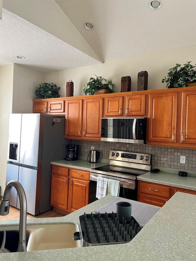 160 Calabay Parc Blvd, Davenport, FL 33897 - kitchen featuring appliances with stainless steel finishes, tasteful backsplash, brown cabinetry, recessed lighting, and a textured ceiling