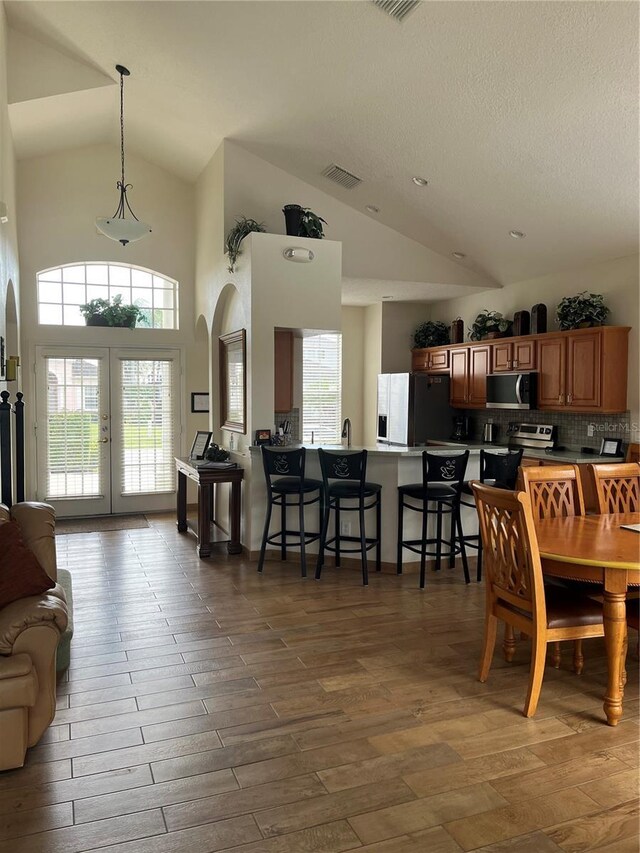 160 Calabay Parc Blvd, Davenport, FL 33897 - dining space with lofted ceiling, arched walkways, french doors, wood finished floors, and a textured ceiling