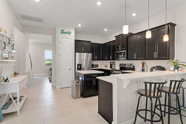 1787 White Feather Loop, Oakland, FL 34787 - kitchen with stainless steel appliances, light countertops, dark cabinets, a peninsula, and a breakfast bar area