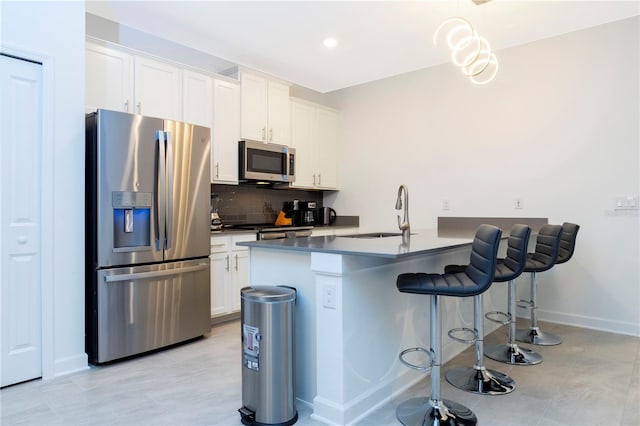 1070 Splash Shot Pl, Davenport, FL 33896 - kitchen with appliances with stainless steel finishes, a sink, a kitchen bar, backsplash, and white cabinets