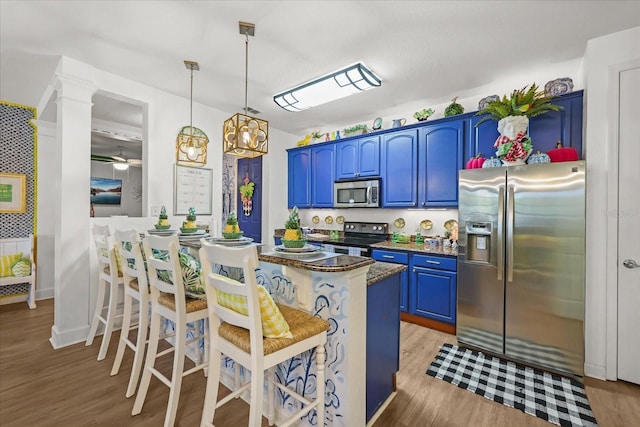 5012 Shoreway Loop Unit 10107, Orlando, FL 32819 - kitchen with stainless steel appliances, blue cabinetry, light wood finished floors, a breakfast bar, and hanging light fixtures
