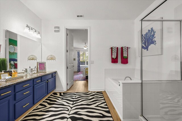 5012 Shoreway Loop Unit 10107, Orlando, FL 32819 - ensuite bathroom featuring wood finished floors, vanity, a garden tub, a stall shower, and baseboards