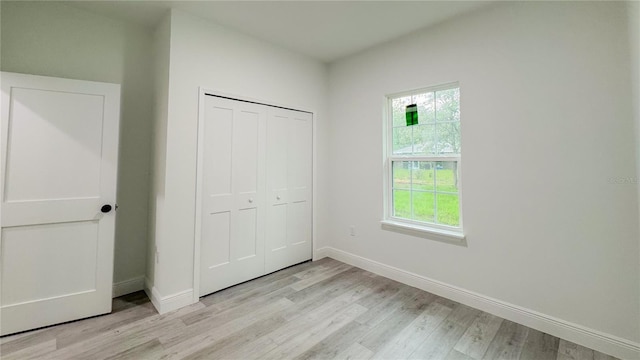 2486 W Magenta Dr, Citrus Springs, FL 34434 - unfurnished bedroom with light wood finished floors, multiple windows, and a closet