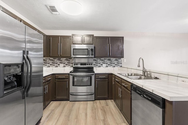 2825 NW 104th Ct Unit B, Gainesville, FL 32606 - kitchen featuring appliances with stainless steel finishes, a sink, dark brown cabinetry, and light wood-type flooring