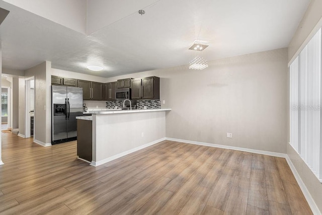 2825 NW 104th Ct Unit B, Gainesville, FL 32606 - kitchen featuring stainless steel appliances, light countertops, light wood-type flooring, a peninsula, and tasteful backsplash