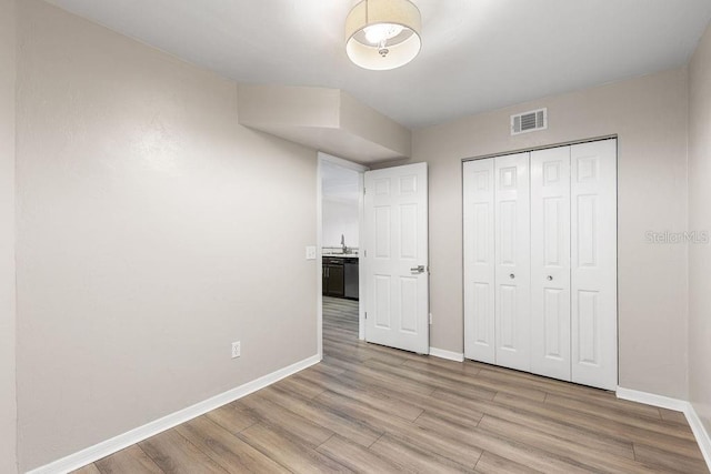 2825 NW 104th Ct Unit B, Gainesville, FL 32606 - unfurnished bedroom featuring baseboards, light wood-type flooring, a closet, and a sink