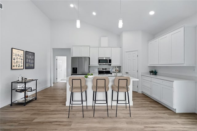 436 Caraway Dr, Kissimmee, FL 34759 - kitchen featuring stainless steel appliances, high vaulted ceiling, a kitchen bar, white cabinets, and light countertops