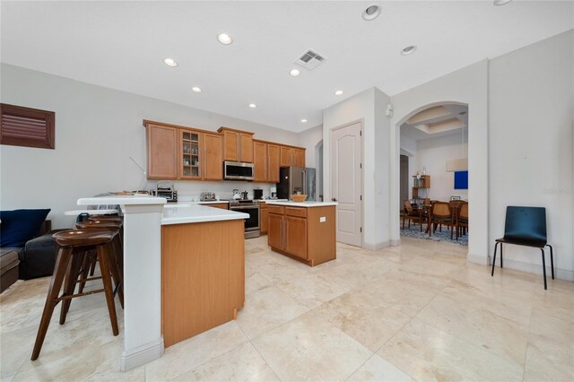 8108 Via Bella Notte, Orlando, FL 32836 - kitchen with appliances with stainless steel finishes, brown cabinets, arched walkways, glass insert cabinets, and a kitchen island