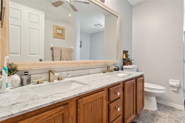 176 Hidden View Dr, Groveland, FL 34736 - bathroom with toilet, double vanity, baseboards, a ceiling fan, and stone finish flooring