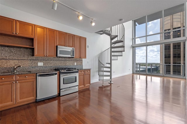 150 E Robinson St Unit 1023, Orlando, FL 32801 - kitchen with stainless steel appliances, backsplash, dark wood finished floors, dark stone countertops, and brown cabinets