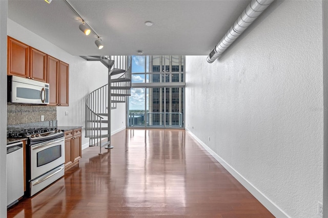 150 E Robinson St Unit 1023, Orlando, FL 32801 - kitchen featuring appliances with stainless steel finishes, a textured wall, decorative backsplash, brown cabinetry, and expansive windows