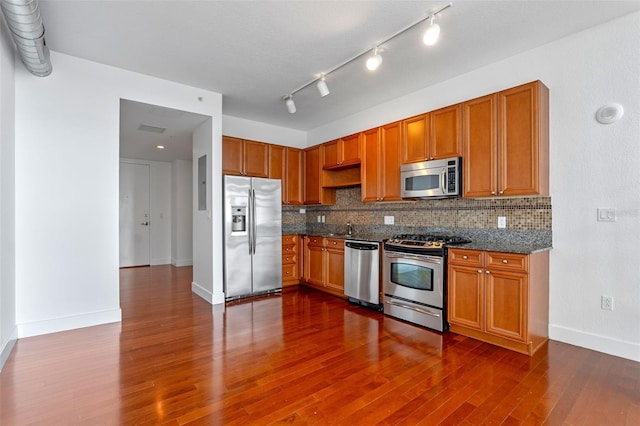 150 E Robinson St Unit 1023, Orlando, FL 32801 - kitchen with stainless steel appliances, decorative backsplash, dark wood-type flooring, and brown cabinetry