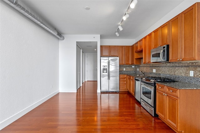 150 E Robinson St Unit 1023, Orlando, FL 32801 - kitchen featuring appliances with stainless steel finishes, decorative backsplash, dark wood-style floors, and dark stone countertops