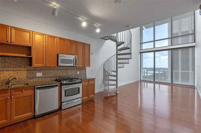 150 E Robinson St Unit 1023, Orlando, FL 32801 - kitchen featuring appliances with stainless steel finishes, tasteful backsplash, dark wood-style floors, dark stone counters, and brown cabinetry