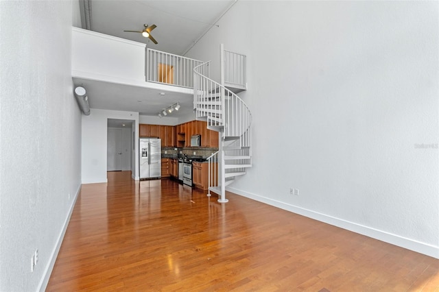 150 E Robinson St Unit 1023, Orlando, FL 32801 - unfurnished living room with stairway, a high ceiling, ceiling fan, light wood-style flooring, and a textured wall