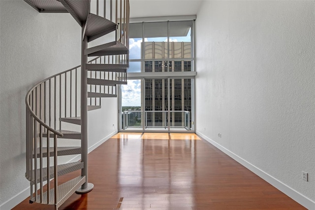 150 E Robinson St Unit 1023, Orlando, FL 32801 - unfurnished living room with a textured wall, stairway, wood finished floors, and a wall of windows