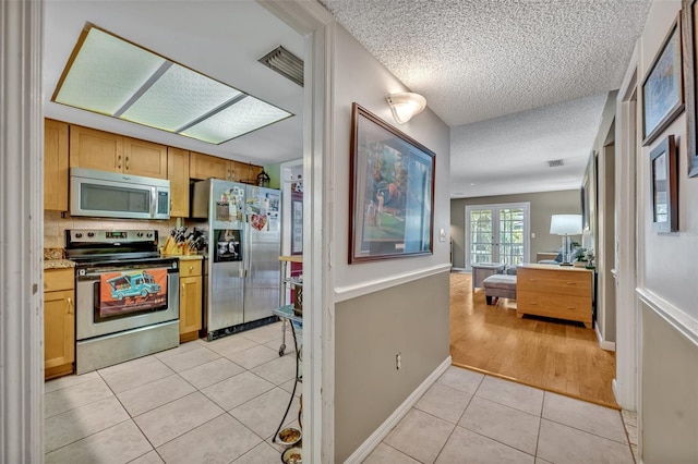 210 Magnolia Rd Unit 214, Maitland, FL 32751 - kitchen featuring appliances with stainless steel finishes, light tile patterned flooring, a textured ceiling, open floor plan, and light countertops