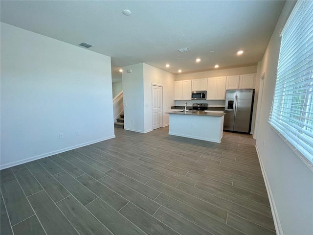 15579 Water Spring Blvd, Winter Garden, FL 34787 - kitchen featuring appliances with stainless steel finishes, open floor plan, dark countertops, white cabinetry, and dark wood finished floors
