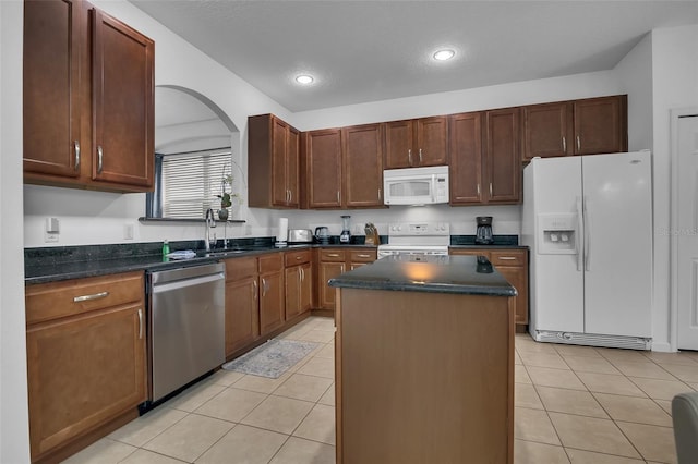 381 Cabello Dr, Davenport, FL 33837 - kitchen with white appliances, a kitchen island, light tile patterned floors, recessed lighting, and arched walkways