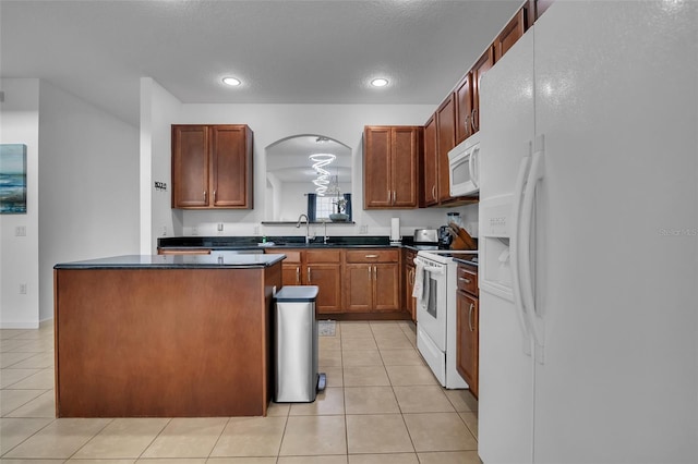 381 Cabello Dr, Davenport, FL 33837 - kitchen featuring white appliances, dark countertops, arched walkways, a kitchen island, and a sink