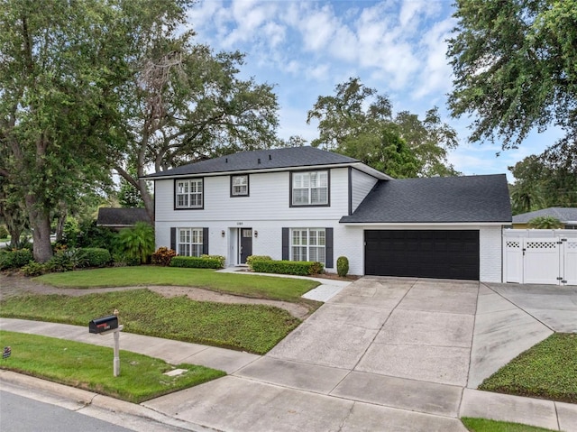 1105 Appleton Ave, Orlando, FL 32806 - colonial home featuring an attached garage, driveway, brick siding, and a gate