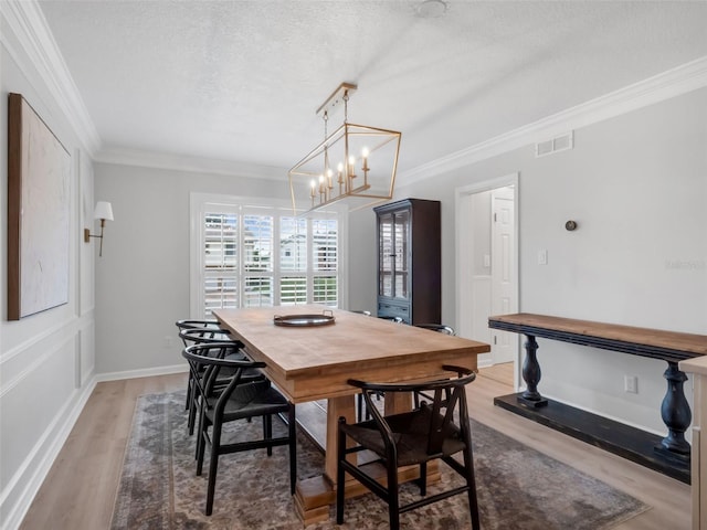1105 Appleton Ave, Orlando, FL 32806 - dining room featuring crown molding, light wood-style floors, a chandelier, and a textured ceiling