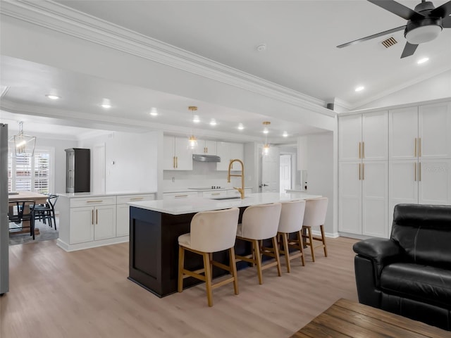 1105 Appleton Ave, Orlando, FL 32806 - kitchen with light wood finished floors, crown molding, open floor plan, a kitchen island with sink, and light countertops