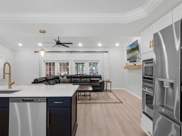 1105 Appleton Ave, Orlando, FL 32806 - kitchen featuring appliances with stainless steel finishes, crown molding, light wood-style floors, light countertops, and white cabinetry