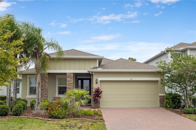 363 Miro Dr, Davenport, FL 33837 - view of front of home with decorative driveway, a garage, stone siding, stucco siding, and roof with shingles