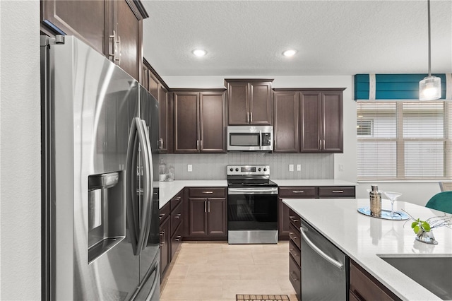 363 Miro Dr, Davenport, FL 33837 - kitchen featuring appliances with stainless steel finishes, dark brown cabinetry, pendant lighting, a textured ceiling, and backsplash