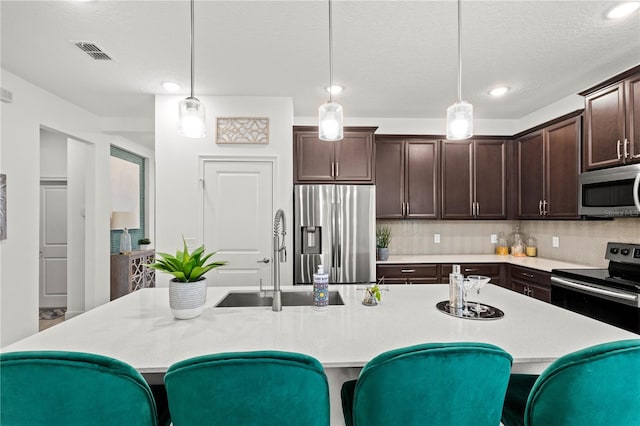 363 Miro Dr, Davenport, FL 33837 - kitchen featuring stainless steel appliances, dark brown cabinetry, pendant lighting, tasteful backsplash, and a kitchen breakfast bar
