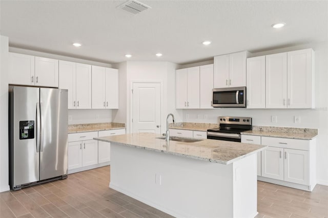1732 Brekey Way, Zephyrhills, FL 33541 - kitchen featuring appliances with stainless steel finishes, wood tiled floors, white cabinetry, recessed lighting, and a kitchen island with sink
