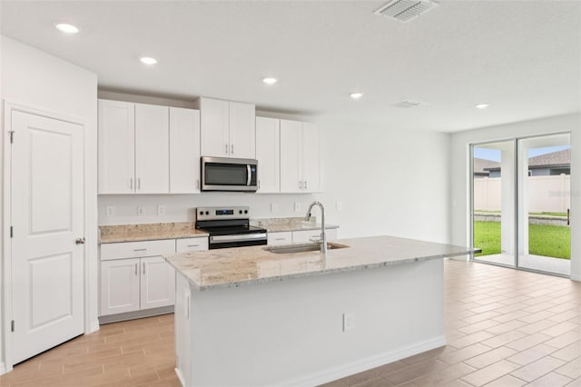 1732 Brekey Way, Zephyrhills, FL 33541 - kitchen with range with electric stovetop, stainless steel microwave, white cabinets, light stone countertops, and recessed lighting