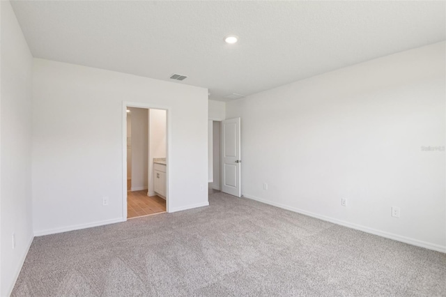 1732 Brekey Way, Zephyrhills, FL 33541 - unfurnished bedroom featuring light colored carpet, recessed lighting, and ensuite bathroom