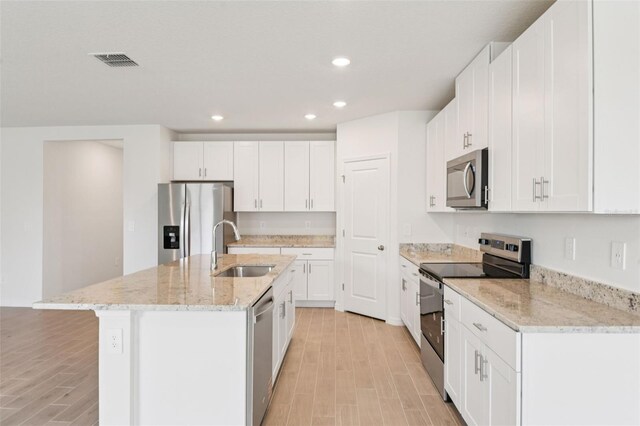 1732 Brekey Way, Zephyrhills, FL 33541 - kitchen with stainless steel appliances, light wood-style flooring, recessed lighting, a kitchen island with sink, and white cabinets