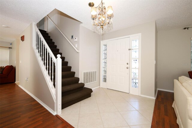 2205 Wyndam Way, Kissimmee, FL 34743 - entrance foyer with stairs, a textured ceiling, a chandelier, and wood finished floors