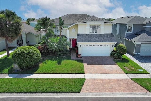 2205 Wyndam Way, Kissimmee, FL 34743 - view of front facade featuring stucco siding, decorative driveway, roof with shingles, a front yard, and an attached garage