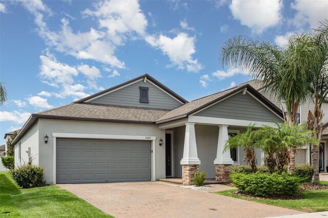 13209 Haystack Ct, Riverview, FL 33579 - view of front of property with stucco siding, a garage, decorative driveway, a shingled roof, and covered porch