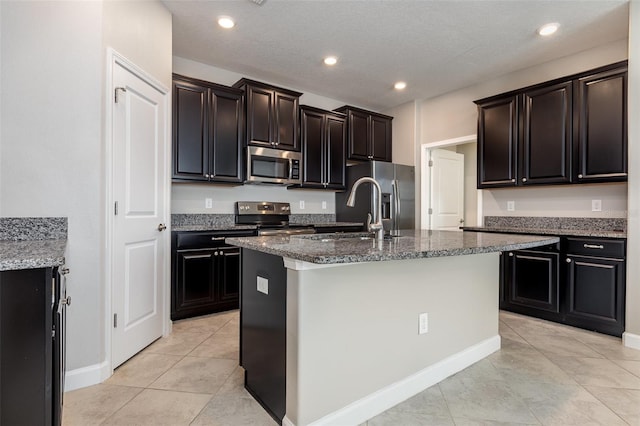 13209 Haystack Ct, Riverview, FL 33579 - kitchen with stainless steel appliances, dark stone countertops, light tile patterned floors, a center island with sink, and recessed lighting
