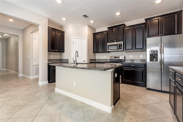 13209 Haystack Ct, Riverview, FL 33579 - kitchen featuring appliances with stainless steel finishes, dark stone counters, light tile patterned floors, a center island with sink, and recessed lighting