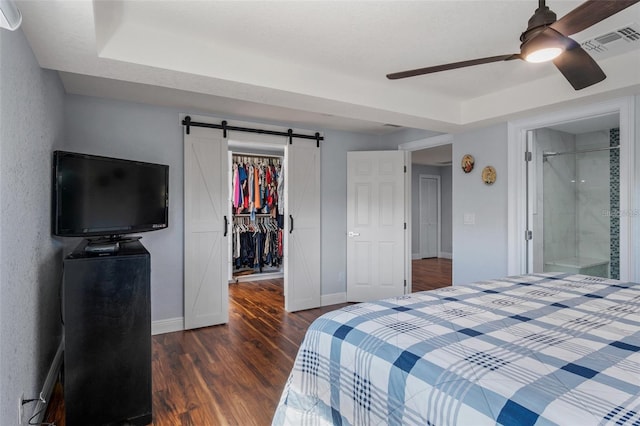 40140 Swift Rd, Eustis, FL 32736 - bedroom featuring a spacious closet, dark wood finished floors, a closet, a barn door, and baseboards
