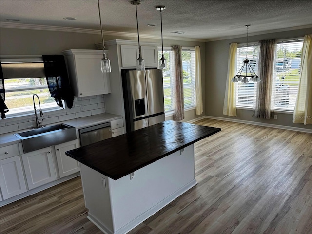 227 Bay St, Port St Joe, FL 32456 - kitchen featuring stainless steel appliances, a sink, backsplash, ornamental molding, and a textured ceiling