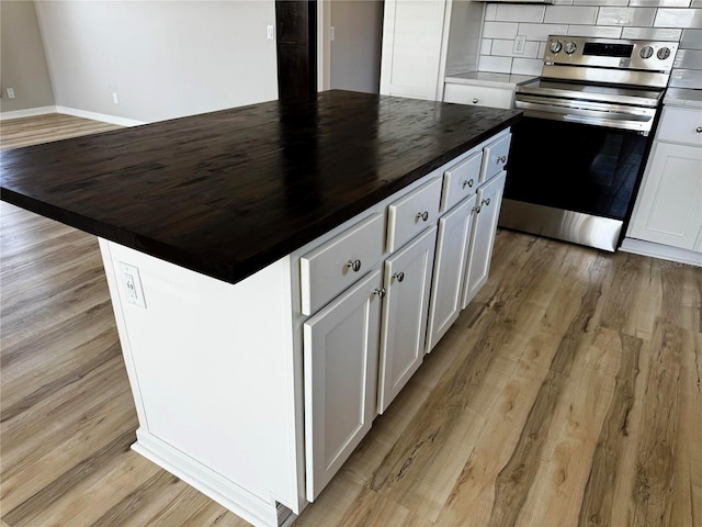 227 Bay St, Port St Joe, FL 32456 - kitchen featuring stainless steel range with electric cooktop, butcher block countertops, a center island, white cabinets, and light wood-type flooring
